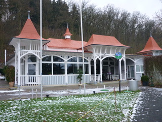 Historisches Gebäude mit frischem weißen Fassadenanstrich und roten Dächern, umgeben von winterlicher Landschaft.