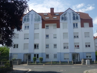 Mehrfamilienhaus mit frisch renovierter WDVS-Fassade in Weiß und Hellblau, rotem Ziegeldach und klarer, moderner Linienführung.