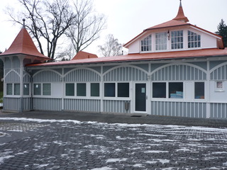 Historisches Gebäude mit frisch renovierter Fassade, grauweißem Holzdekor und rotbraunem Dach – klassisches Design mit modernem Anstrich.